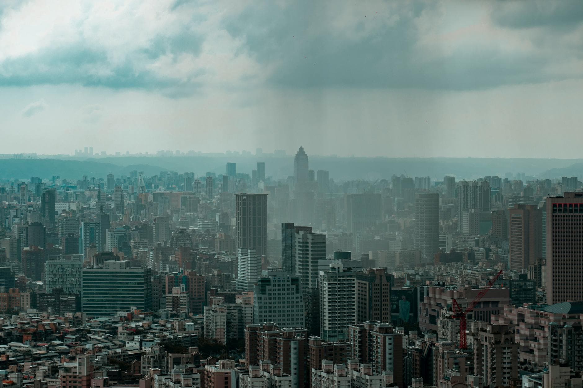 Dramatic city skyline under a cloudy sky, showcasing modern architecture and urban density.